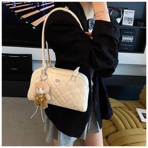 Détail du sac à main matelassé blanc cassé avec breloque ours et texture en cuir souple