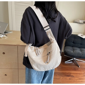 Back view of a person wearing a beige crescent canvas bag with textured fabric detail