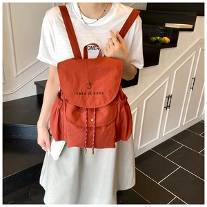 Détail d'un sac à dos seau en toile rouge rouille avec cordon et broderie décorative