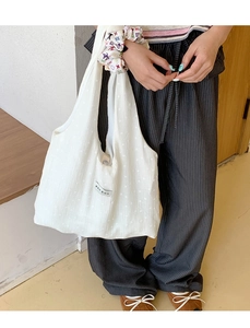 Close-up of white canvas tote bag with small flower patterns and Korean text label