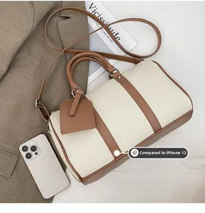 Detailed size comparison of the contrast Boston bag next to an iPhone 12 for reference
