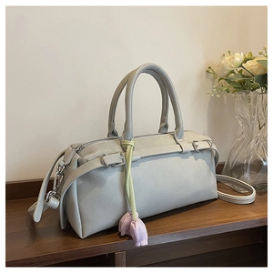 Detailed view of light gray pebble leather bag with a tulip charm and silver hardware