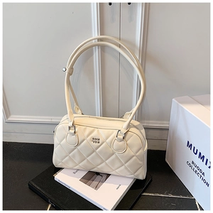 Détail de la texture en cuir matelassé et du logo en métal sur le sac beige