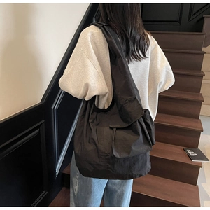 Detail of black nylon tote bag with unique wrinkled texture and wide shoulder strap