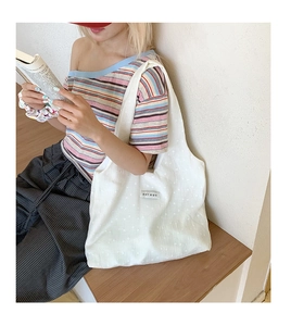 Close-up of beige tote bag featuring textured fabric and white polka dot pattern detail