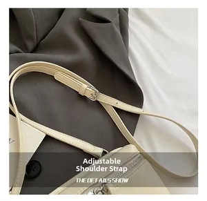 Detail shot of the adjustable leather strap with silver metal buckle on a beige square bag