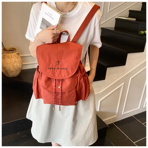 Détail du sac à dos en toile rouge avec broderie présenté dans un cadre de vie réel