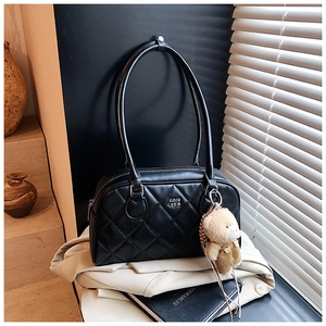 Détail du sac cabas en cuir noir matelassé avec logo en métal et breloque ours mignon