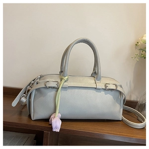 Close-up of light grey litchi grain leather bowling bag with a purple tulip charm detail
