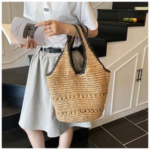 Detailed close-up showing texture of the handmade straw tote bag with black braided handles