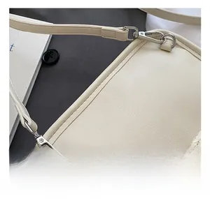 Detail showing high-quality polished silver metal hook on beige litchi grain leather bag