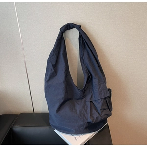 Close-up of a charcoal grey nylon tote bag with wide strap and side cargo pocket detail