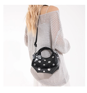 Detail view of black faux leather crescent bag with silver rivets and bow ornament