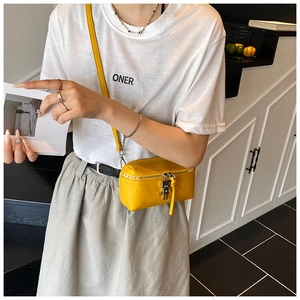 Detail of yellow rectangular crossbody bag with silver robot pendant on white t-shirt
