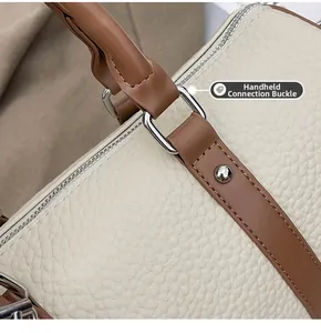 Detail of silver square metal buckle and lychee grain leather on a Boston style handbag
