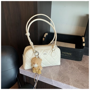 Gros plan du sac fourre-tout crème matelassé avec un ours en peluche et un logo circulaire