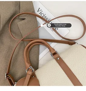 Detail view of cream lychee texture leather handbag with adjustable brown shoulder strap
