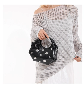 Détail du sac à bandoulière en vernis noir avec rivets argentés et nœud décoratif