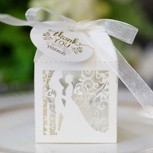 Macro view of white laser-cut wedding favor box with Mr & Mrs design and gold thank you tag
