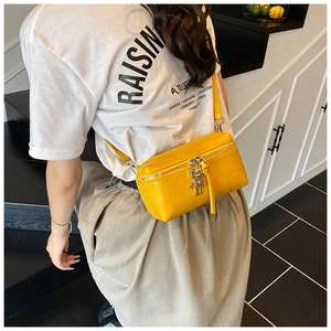 Crossbody view of a mini yellow square bag with robot charm and leather strap