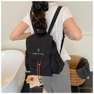 Vue détaillée du sac à dos en toile noire avec broderie rose et cordons rayés