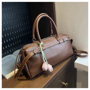 Detail view of brown pebbled leather Boston bag with pink tulip charms and metal hardware