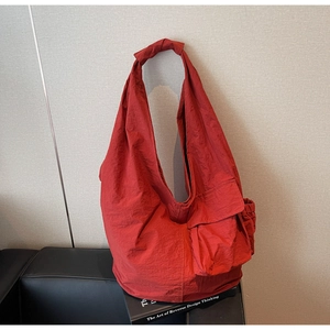 Detail view of red textured nylon tote bag with large capacity and knotted shoulder strap