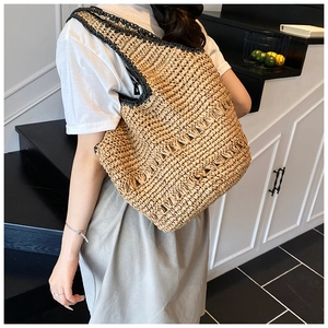 Close-up of a straw tote bag with black woven trim details and spacious interior texture