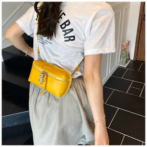 Detail of yellow box crossbody bag featuring a silver zipper and a metal robot charm