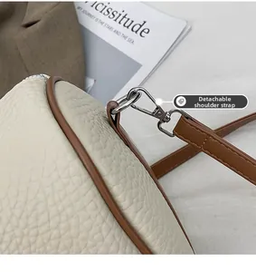Detail of detachable brown shoulder strap on white lychee grain retro handbag