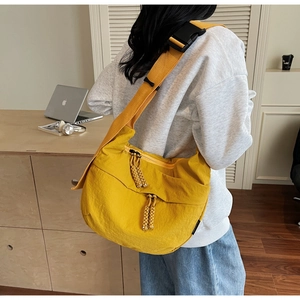 Detailed back view of a ginger yellow nylon crossbody bag with wide adjustable shoulder strap