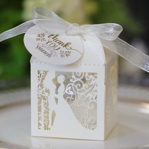 Detail of laser-cut white wedding favor box with Mr & Mrs silhouette and thank you tag