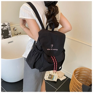 Détail du sac à dos en nylon noir avec broderie rose et cordons de serrage