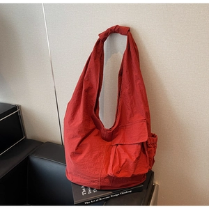 Detail of burgundy tote bag showing knotted shoulder strap and textured nylon fabric