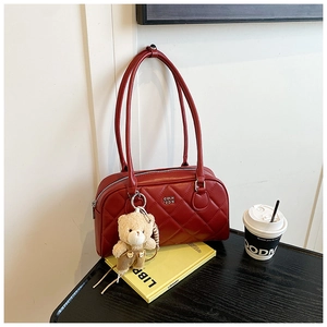 Detailed close-up of dark red quilted bowling bag with cute bear charm and metal logo