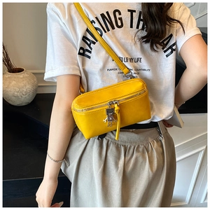 Detail of a bright yellow mini crossbody bag featuring a silver robot metal pendant zip