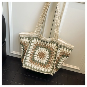 Close-up of handmade crochet tote bag featuring multi-color floral pattern and woven strap