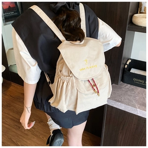 Détail du sac à dos en toile beige avec broderie take it easy et cordons rayés rouge et blanc