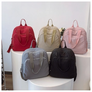 Mochilas de nailon en rojo, beige, rosa, gris y negro sobre bases blancas