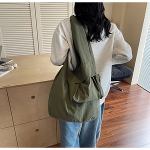 Detail view of olive green oversized tote bag with side pleats shown on shoulder