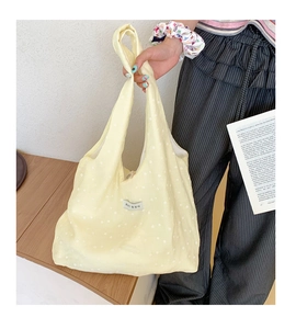 Close-up of yellow canvas tote bag with white floral pattern and minimal Korean label