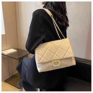 Detail of beige quilted shoulder bag featuring gold chain strap and metal turn-lock