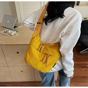 Detailed back view of a yellow canvas crossbody bag with wide strap and woven zippers