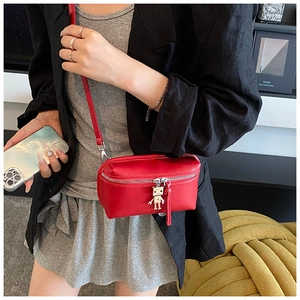 Detail of red mini crossbody bag featuring a unique silver metal robot charm accessory
