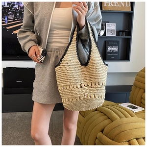 Detail of hand-woven straw tote bag with black crochet trim and intricate cutout texture