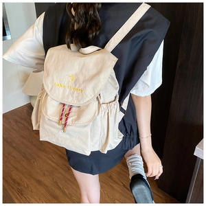 Sac à dos beige en nylon porté par un mannequin avec broderie 'take it easy' et cordon rouge