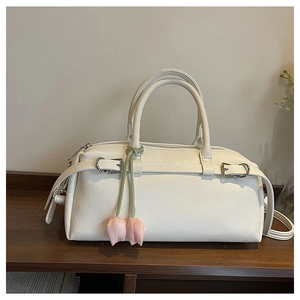 Detail of white lychee leather Boston bag featuring a cute pink tulip charm and buckles