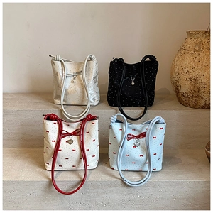 Detail of canvas bucket bags with bow designs, heart charms and pearl accents