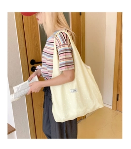 Close-up of a pale yellow canvas tote bag with a minimalist stitched fabric label