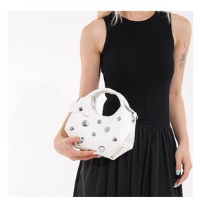 Détail du sac à main blanc avec clous métalliques argentés et un nœud décoratif